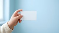 Hand holding blank white business card against soft blue background, ideal for branding and corporate identity mockups.