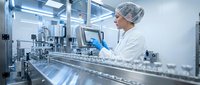 Male scientist in sterile laboratory environment operating pharmaceutical manufacturing equipment with precision and focus.