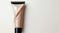 Luxurious beige cosmetic tube with black cap on light background, elegant minimal composition showing beauty product packaging with glossy texture and folds.
