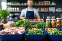 Fresh ingredients and raw meat displayed in blue bowls at butcher shop counter with smiling male butcher in apron working in background for culinary business.