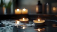 Relaxing spa atmosphere with burning candles creating warm ambient lighting on wet stone surface for wellness and meditation practices.