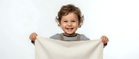 Happy toddler boy with curly brown hair holding white fabric blanket, smiling joyfully on isolated background for childcare and textile design projects.