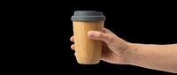 Hand holding a reusable bamboo coffee cup with gray silicone lid, isolated on transparent background. Great for eco, cafe, and sustainability clipart, stickers, print on demand.