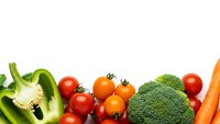 Fresh organic vegetables including broccoli, bell peppers, cherry tomatoes and carrots arranged on white background for healthy cooking and nutrition concepts.