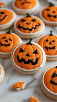 Halloween pumpkin face cookies with orange icing and black carved expressions on white background for seasonal baking and party treats.