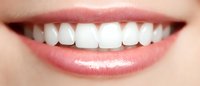 Close up view of healthy white teeth and pink lips showing bright smile with straight aligned teeth and natural pink lipstick makeup.