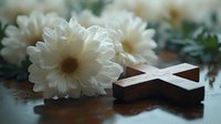 Wooden cross lying beside white chrysanthemum flowers on dark reflective surface, creating peaceful spiritual atmosphere for religious ceremonies and memorials.