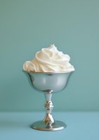Whipped cream served in vintage silver goblet against soft teal background, perfect for dessert, bakery, and food styling projects.