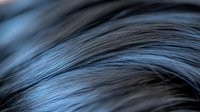 Close-up of flowing dark hair strands with blue highlights creating smooth waves and natural texture for beauty and haircare concepts.