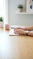 Woman hands typing on wireless keyboard at modern home office desk with pink coffee mug and green plants creating productive workspace atmosphere.