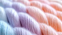 Colorful cotton yarn skeins in pastel rainbow hues arranged in rows, soft textile fibers for knitting, crocheting and handicraft projects.