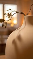 Minimalist ceramic vase with dried branch creating warm bokeh lighting atmosphere for modern interior design and home decoration concepts.