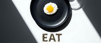 Fried egg on black plate with word EAT made from seeds on white surface, dramatic shadows, minimalist food concept top view.