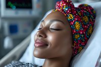 African woman with colorful headwrap resting peacefully in hospital bed, showing resilience and calm during medical treatment.