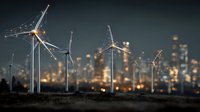 Wind turbines generating clean renewable energy with illuminated city skyline in background during evening hours creating sustainable power solution.