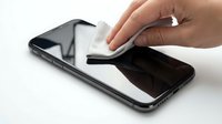 Person cleaning smartphone screen with microfiber cloth, isolated on white background for technology and device care concepts.