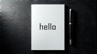 White notebook with hello text beside a sleek pen on dark stone surface, minimalist greeting concept for business and personal branding.