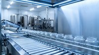Modern pharmaceutical manufacturing facility with stainless steel equipment and glass vials on automated production line for medical industry applications.