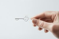 Female hand holding tiny decorative silver key against white background, minimalist composition showing delicate details and gentle grasp. Suitable for security concepts.