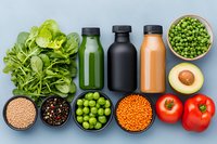 Fresh healthy ingredients and smoothie bottles on gray background. Raw organic vegetables, legumes and juice drinks for detox diet and clean eating.