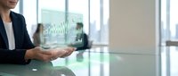 Professional businesswoman analyzing financial data charts on tablet device in modern corporate office environment for strategic planning and decision making.