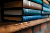 Old hardcover books with blue and brown spines arranged on wooden shelf, shallow depth of field creates atmospheric library ambiance for education and literature concepts.