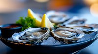 Freshly shucked oysters served on dark plate with lemon wedges and parsley garnish, ready for fine dining or seafood restaurant menus.