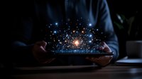 Glowing particles and light dots floating above digital tablet held by person in dark room, creating magical technology visualization effect.