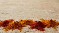 Spice powder mixture of paprika and turmeric arranged in stripes on sand surface for cooking and seasoning backgrounds.