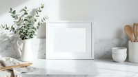 Clean white frame mockup on marble kitchen counter with eucalyptus plant and wooden utensils for home decor and branding presentations.