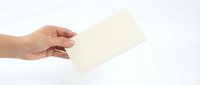 Hand holding blank cream envelope on white background isolated for correspondence and mailing design projects.