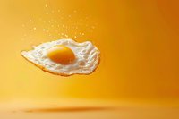 Levitating fried egg with bright yellow yolk floating against vibrant orange background, creative food photography concept for menu design and culinary advertising.