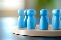 Blue wooden peg dolls arranged in circle on round wooden base, representing teamwork, community, or social connection concept.