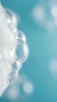 White foam bubbles on turquoise water surface with soft bokeh background for spa wellness skincare and relaxation concepts.