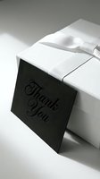 Elegant white gift box with white ribbon and black thank you card, monochrome luxury packaging concept for weddings, holidays, and corporate gifting.