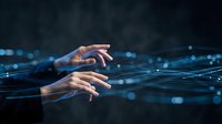 Hands reaching toward glowing blue digital network lines on dark background, symbolizing technology connection and data transfer.