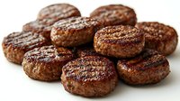 Grilled beef patties with charred grill marks and caramelized surface arranged in group, showing juicy texture and seasoned meat for restaurant menu or cooking.