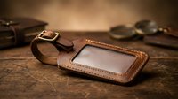 Handcrafted leather luggage tag with clear window on rustic wooden surface. Premium travel accessory for baggage identification and personalization.