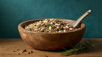 Mixed legumes and grains in rustic wooden bowl with spoon on kitchen counter. Healthy protein-rich ingredients for cooking and meal preparation.