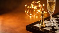 Elegant champagne glass and golden trophy on chess board with warm bokeh lights creating luxurious celebration atmosphere for victory and success concepts.