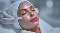 Professional facial treatment with serum application by cosmetologist in modern spa clinic for skincare and beauty enhancement procedures.