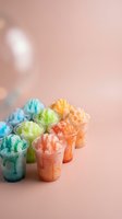 Colorful shaved ice cups arranged in rows featuring blue, green, yellow, and orange flavors against soft pink background with bokeh lights, suitable for beverage, summer, and food service marketing.