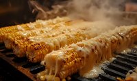 Grilled corn on the cob with melted cheese and steam rising from barbecue grill. Fresh summer street food cooking outdoors with golden kernels and creamy topping.