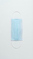 Single light blue surgical face mask with elastic ear loops isolated on white background, ready for healthcare, medical, and safety design projects.