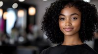 Young African American businesswoman with curly hair smiling confidently in modern office environment for professional corporate marketing materials.