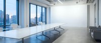Modern conference room with white table and chairs overlooking city skyline through floor-to-ceiling windows in contemporary office space.