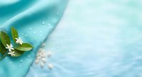 Spa wellness background with green leaves, white flowers and water drops on soft blue fabric creating peaceful relaxation atmosphere for beauty treatments.