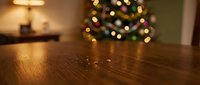 Wooden table surface with blurred Christmas tree lights in cozy home interior background for holiday product display and festive seasonal decorations.