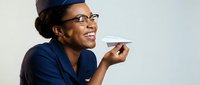 African American female healthcare worker in blue scrubs and surgical cap smiling while holding medical instrument, isolated on white background for design use.
