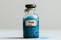 Vintage glass bottle with blue glittering substance labeled "Trust" on white background, symbolizing emotional concepts for therapy, coaching, or relationship content.
